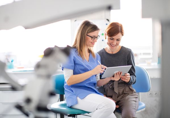 a dentist talking to woman in dentist surgery a de CM8VQGB