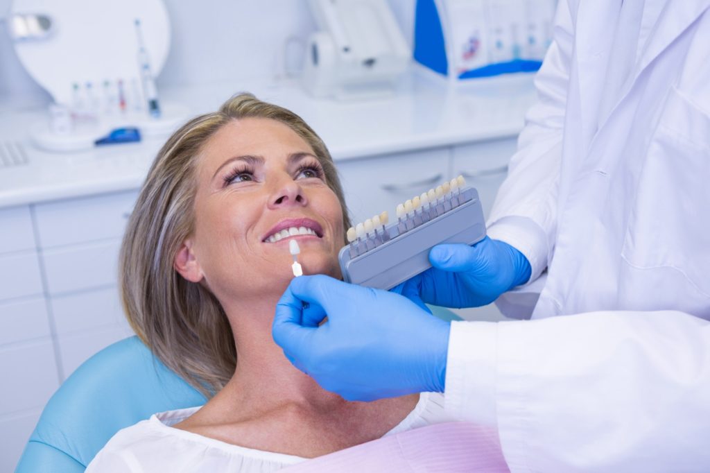 doctor holding tooth whitening equipment by patient