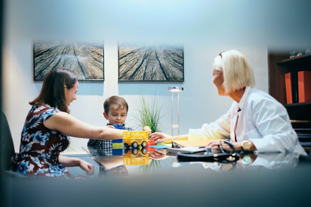 happy doctor woman working and playing with mom and boy