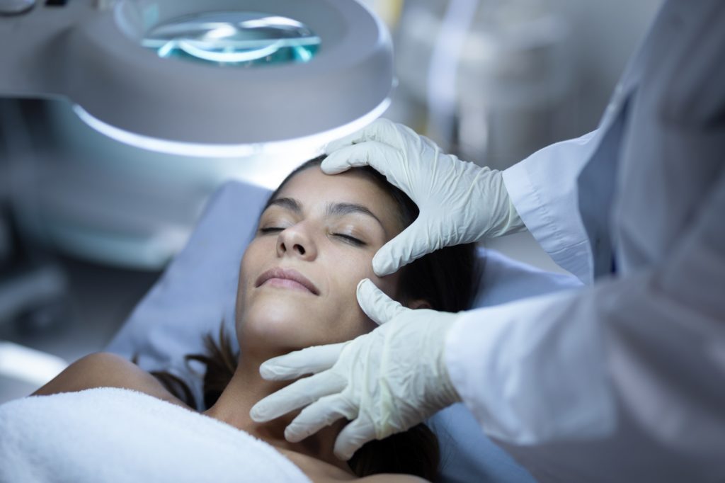 high angle view of a surgeon examining a caucasian patient during plastic surgery in clinic