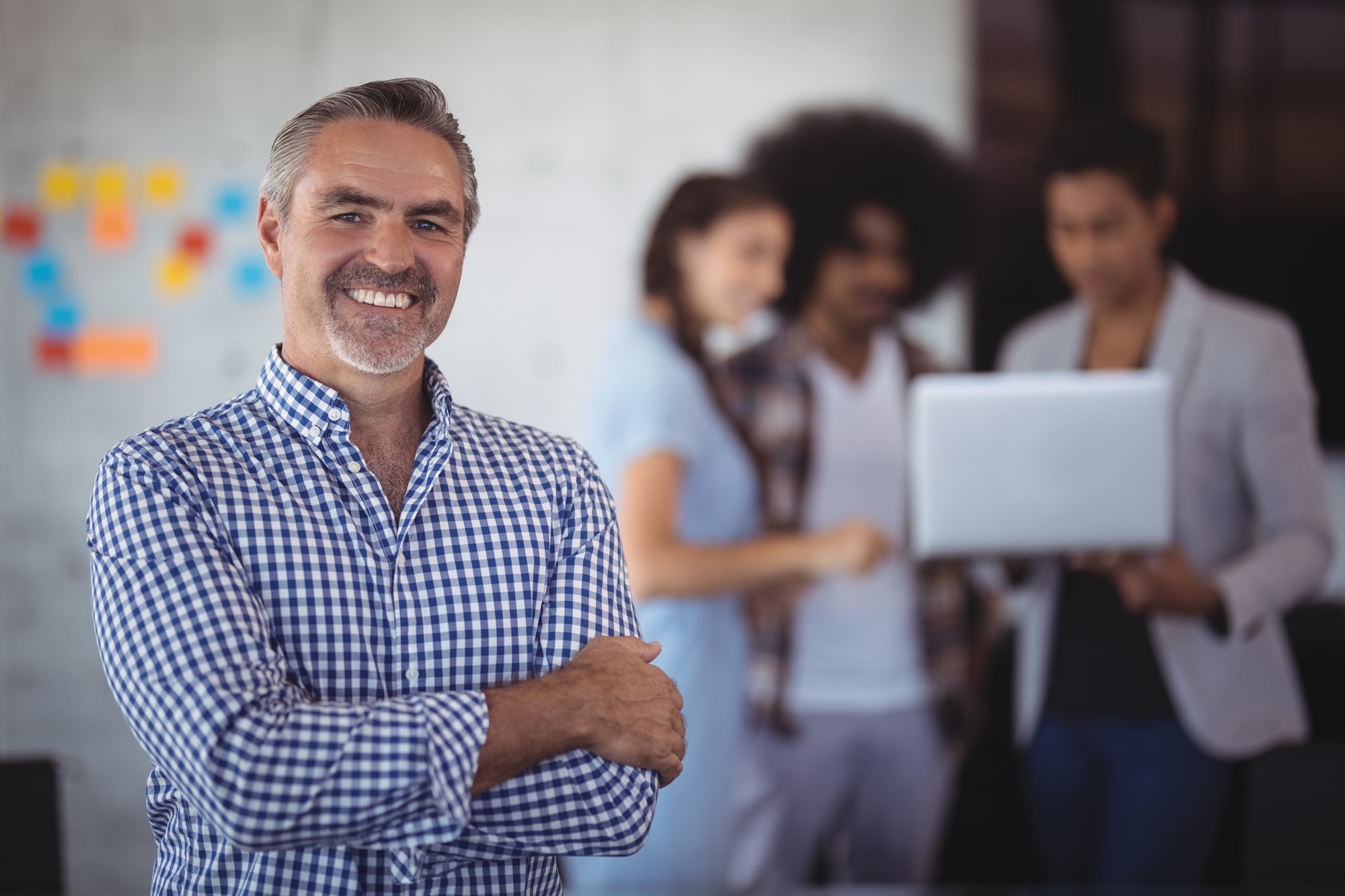 portrait of smiling businessman standing with team in background