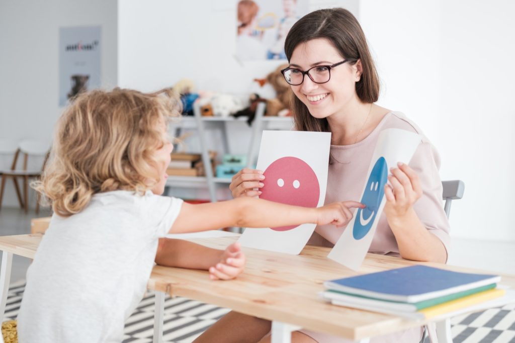 smiling counselor holding pictures during meeting with young pat