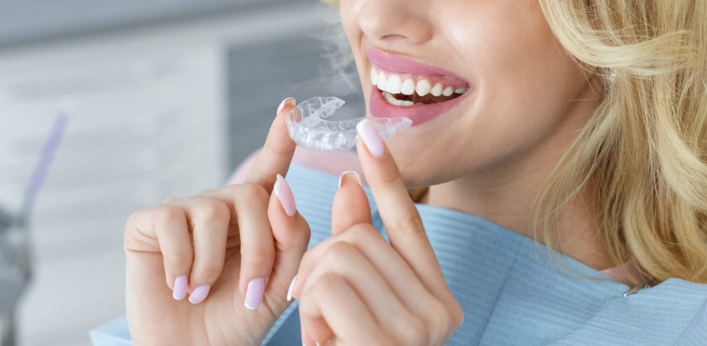 INVISALIGN ALIGNERS 3 Unrecognizable female patient holding invisible braces or trainer, panorama