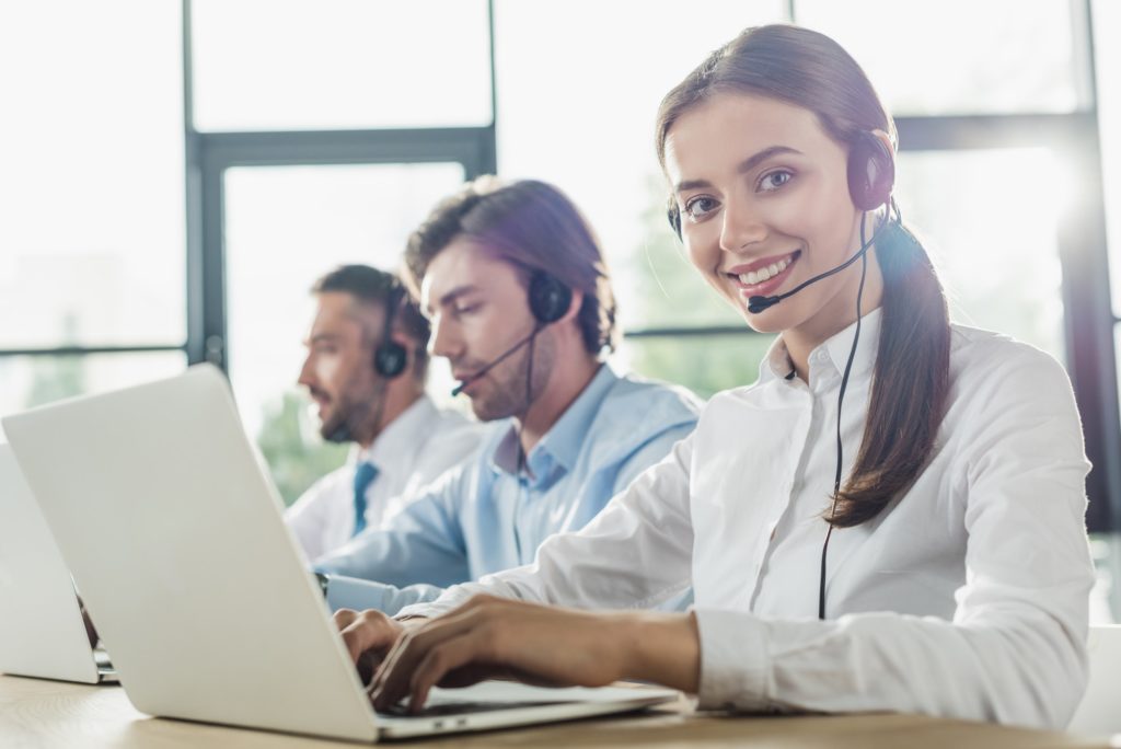 happy call center managers working with laptops and microphones at modern office