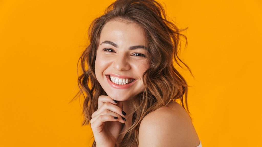 Blanqueamiento Dental Láser con Zoom 24 a woman smiling with her hand on her chin