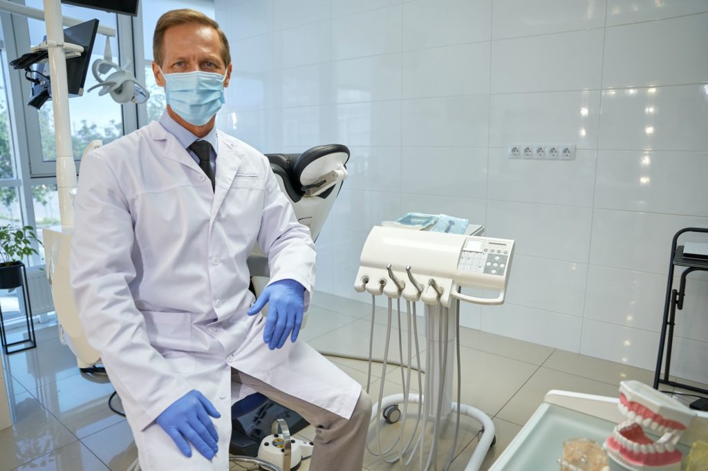 Proud dental specialist in uniform sitting at his office