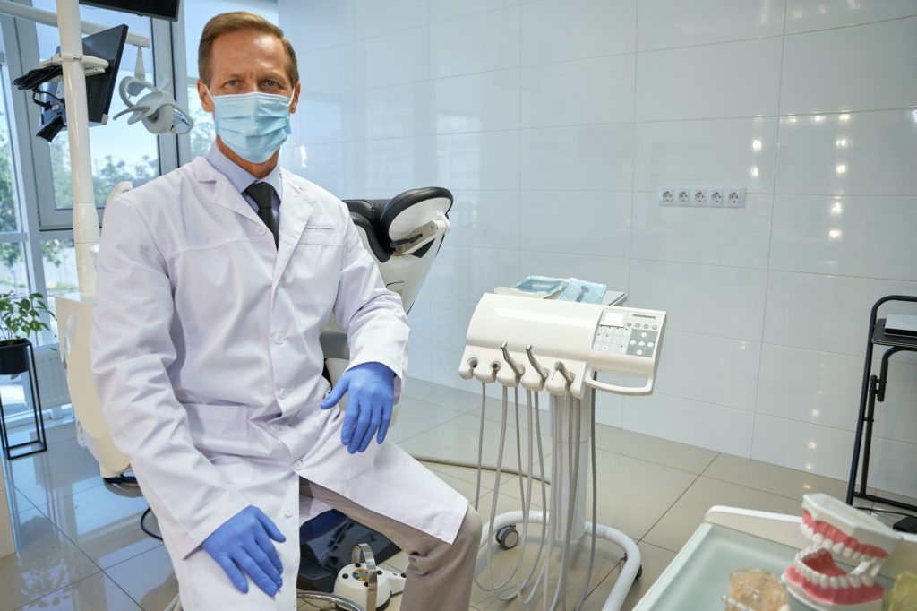 All On 4 Dental Implants 9 Proud dental specialist in uniform sitting at his office